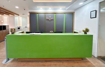 Modern reception area with vibrant green desk and sleek design in Sale Shop coworking space.