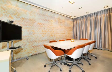 Modern meeting room with stylish chairs, brick accent wall, and privacy curtains.