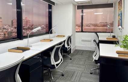 Modern coworking space with ample natural light, ergonomic chairs, and city views.
