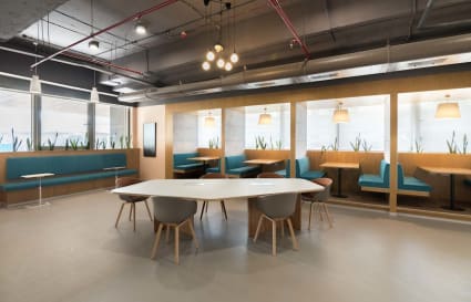 Modern coworking space with cozy booths, ample natural light, and sleek furnishings.