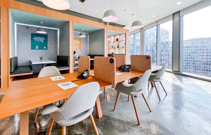 Modern coworking space with open desks and cozy pods, featuring stunning city views.