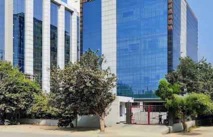 Modern coworking space in Noida featuring sleek glass facade and lush greenery.