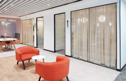 Modern coworking space with vibrant seating, glass-walled meeting rooms, and stylish decor in मुंबई.