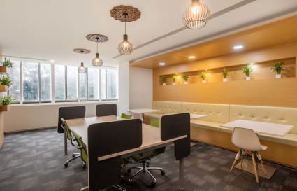 Bright coworking space with modern furnishings, natural light, and greenery accents.