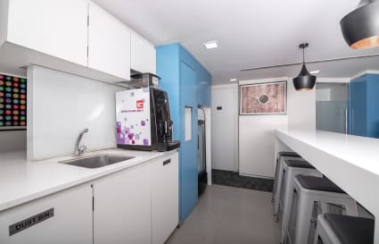 Modern coworking kitchen with sleek design, coffee machine, and ample seating on Sion-Trombay Road.