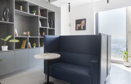 Modern coworking space with cozy seating, natural light, and stylish shelving in Delhi's Phase 1.