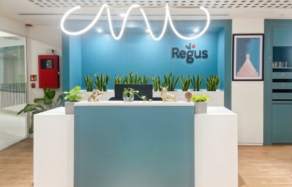 Stylish reception with vibrant decor and lush greenery at a flexible coworking space.