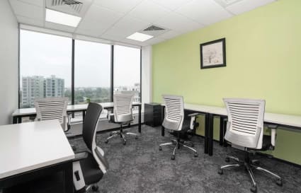 Modern coworking space with natural light, ergonomic chairs, and a vibrant green accent wall.