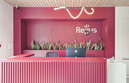 Modern reception area with vibrant red design, sleek desk, and greenery accents.