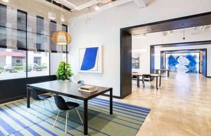 Bright, modern coworking space with open layout, vibrant artwork, and ample natural light.