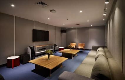 Comfortable breakout area featuring plush seating, flat-screen TV, and modern decor. Ideal for informal meetings.