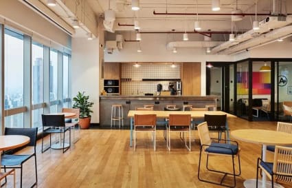 Modern coworking space with natural light, open seating, and a cozy kitchenette in Jakarta.