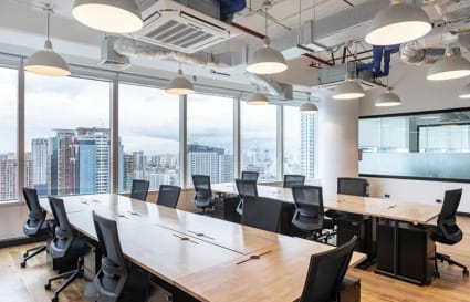 Modern coworking space with large windows, ergonomic chairs, and natural light on Ayala Avenue.