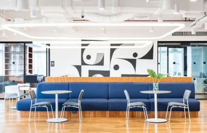 Modern coworking area with vibrant blue seating, sleek tables, and abundant natural light.