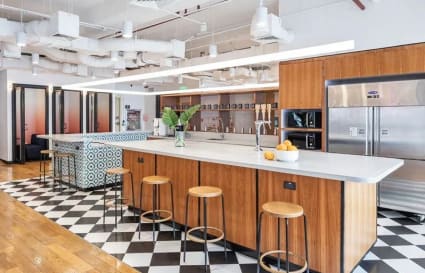 Modern coworking space with stylish kitchen area, ample seating, and vibrant design accents.