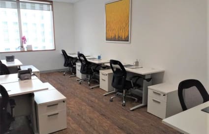 Bright coworking space with modern desks and ergonomic chairs, featuring ample natural light.
