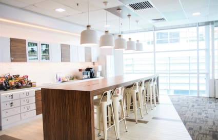 Modern coworking space with a sleek kitchen area and abundant natural light. Ideal for collaboration.