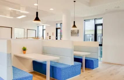 Bright, modern coworking space with cozy booth seating and stylish pendant lighting.