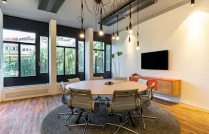 Modern coworking space with stylish round table, ergonomic chairs, and ample natural light.