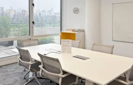 Bright, modern coworking space with natural light, ergonomic chairs, and a city view.