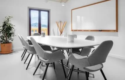 Bright, modern meeting room with natural light and a whiteboard, perfect for collaboration.