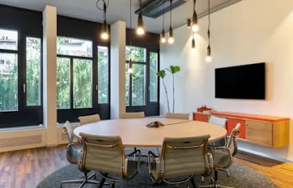 Modern coworking space with stylish lighting, natural light, and a collaborative round table setup.