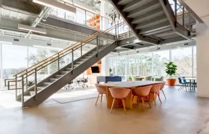 Bright coworking space with modern design, featuring open seating, natural light, and lush views.