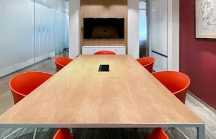 Modern meeting room with vibrant red chairs, sleek table, and glass partitions on Ayala Avenue.