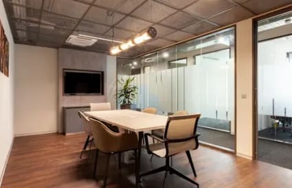 Modern meeting room with sleek glass walls, elegant lighting, and comfortable seating.