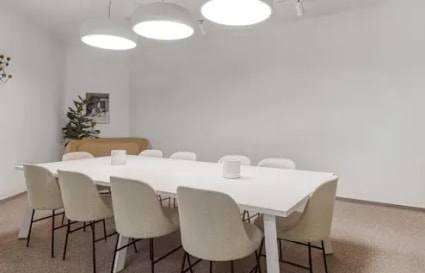 Modern coworking space featuring a sleek conference table, ample seating, and soft lighting.