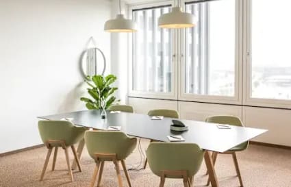 Modern coworking space with natural light, sleek table, and stylish seating for collaboration.
