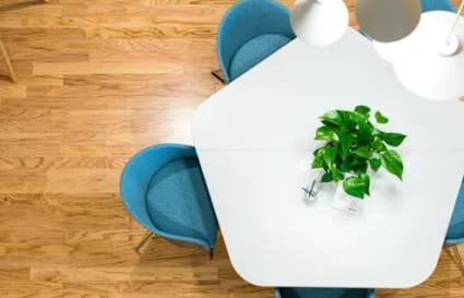 Modern coworking area with a pentagonal table, stylish blue chairs, and bright lighting.