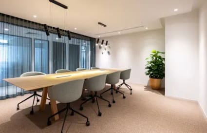 Modern coworking space with a large conference table, stylish chairs, and abundant natural light.