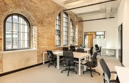 Open, airy coworking space with natural light, exposed brick, and modern furnishings.