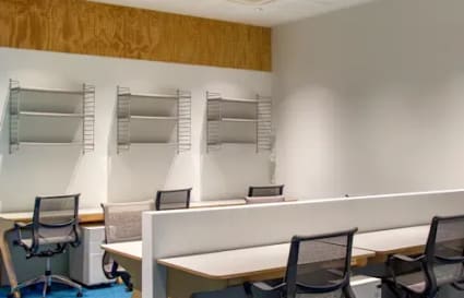 Modern coworking area with sleek desks, ergonomic chairs, and ample shelving. Perfect for productivity.