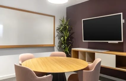 Modern meeting area with cozy seating, a whiteboard, and a TV for presentations.