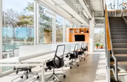Bright coworking space with modern desks, natural light, and a mezzanine area for added flexibility.