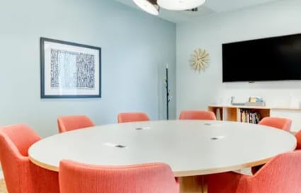 Bright meeting room with modern lighting, vibrant red chairs, and a large conference table.