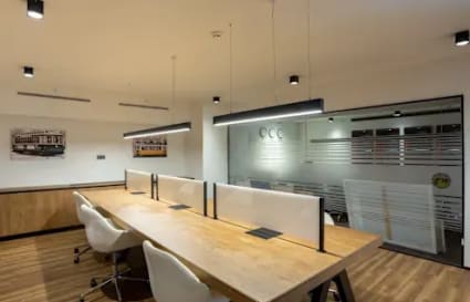 Modern coworking space with sleek wooden desks, stylish chairs, and ambient lighting on Kamarajar Road.