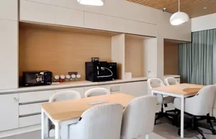 Modern coworking space with sleek furniture, ample lighting, and a functional kitchenette.
