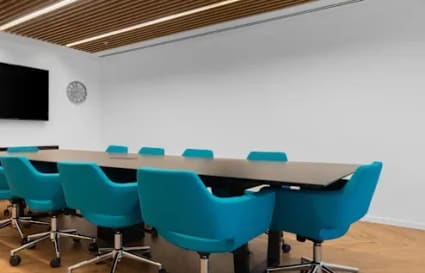Sleek conference area with modern chairs, wooden ceiling, and ample natural light. Ideal for meetings.