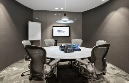 Sleek meeting room with ergonomic chairs, round table, and modern AV setup in Battery Road coworking space.