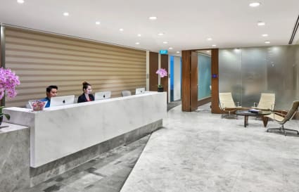 Sleek reception with marble desk and modern seating, offering a professional coworking environment.