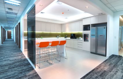 Modern coworking space with sleek kitchen, vibrant seating, and ample natural light.