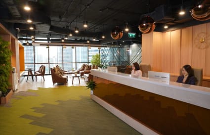 Modern coworking space with ample natural light, vibrant decor, and a welcoming reception.