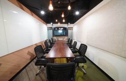 Modern conference room with seating for ten, equipped with a large screen and stylish lighting.