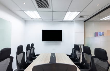 Modern conference room with sleek chairs, large screen, and glass walls. Ideal for meetings.