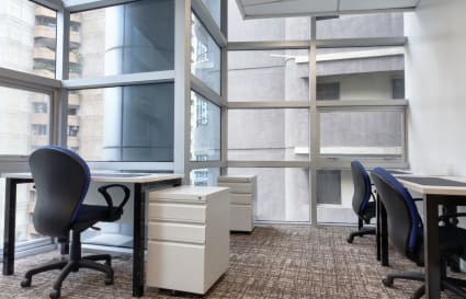 Modern coworking space with floor-to-ceiling windows, comfortable chairs, and ample natural light.