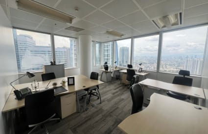 Bright coworking space with panoramic city views, modern desks, and ergonomic chairs.