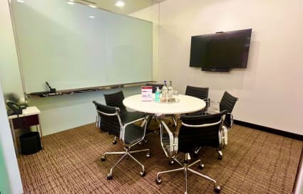 Sleek meeting room with modern chairs, TV, and whiteboard in a flexible Pathum Wan coworking space.